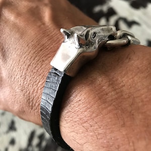 May include: A black leather bracelet with a silver horse head clasp.