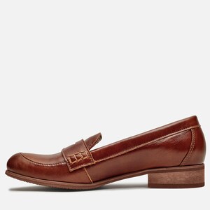 May include: Brown leather loafers with a stitched detail on the vamp. The loafers have a low block heel.