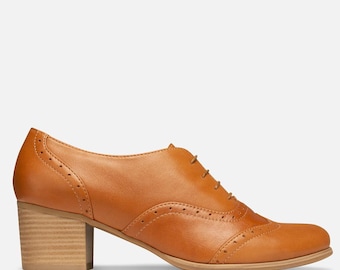 May include: A tan leather oxford shoe with a block heel. The shoe features decorative perforations and a lace-up closure. The heel measures approximately 2.5 inches.