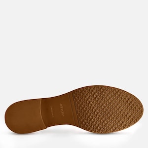 May include: The underside of a brown leather shoe with a textured rubber sole. The sole has the text "Carl by  " printed on it.
