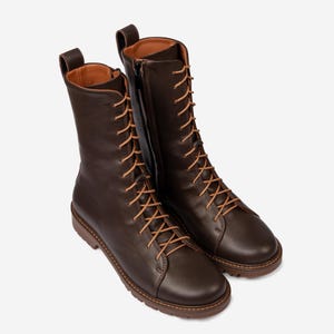 May include: A pair of brown leather lace-up boots with tan laces. The boots have a rounded toe and a chunky heel.