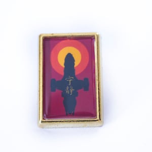 May include: A gold-coloured pin with a red background featuring a silhouette of a spaceship with the Japanese characters "千 尋" in gold. The spaceship is flying through a yellow and orange sun.