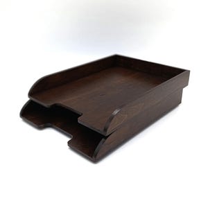 May include: A two-tiered wooden file organiser in a dark brown finish. The organiser has a simple, rectangular design with rounded edges.