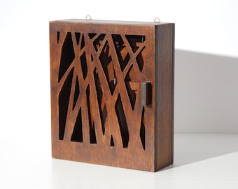 May include: A dark brown wooden box with a geometric cutout design. The box has a hinged lid and a small metal handle.