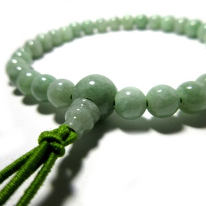 May include: A green jade mala prayer bead necklace with a green cord tassel.