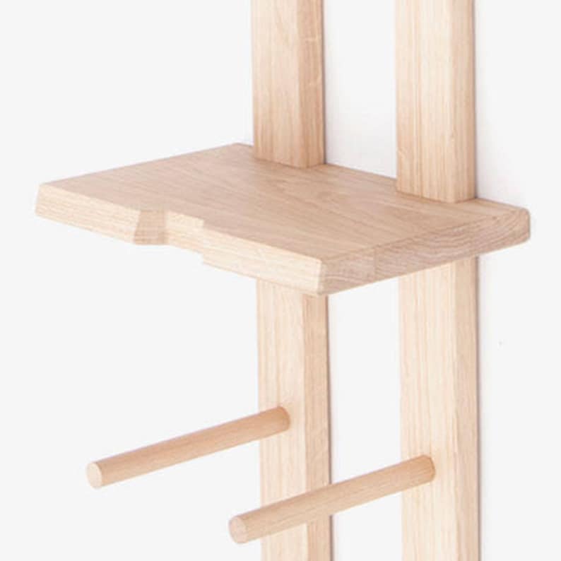 May include: A wooden wall-mounted shelf unit with two shelves and two dowel rods. The shelves are made of light-colored wood and the dowel rods are natural wood.