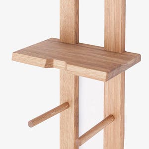 May include: A wooden wall-mounted shelf unit with two shelves and two dowel rods for hanging items. The shelf unit is made of natural wood with a light brown finish.