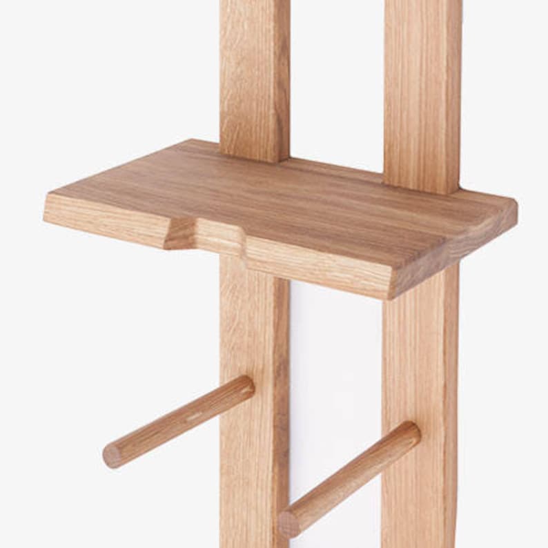 May include: A wooden wall-mounted shelf unit with two shelves and two dowel rods for hanging items. The shelf unit is made of natural wood with a light brown finish.