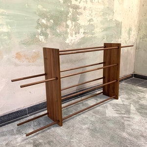 Op de afbeelding: Een houten schoenenrek met vijf planken en een rustieke bruine afwerking. Het rek is gemaakt van massief hout en heeft een eenvoudig, minimalistisch ontwerp.