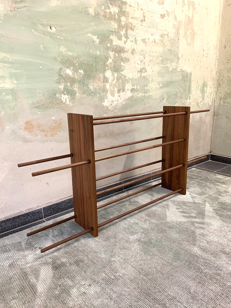 Op de afbeelding: Een houten schoenenrek met vijf planken en een rustieke bruine afwerking. Het rek is gemaakt van massief hout en heeft een eenvoudig, minimalistisch ontwerp.