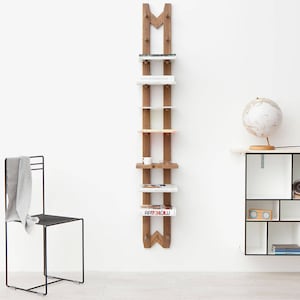May include: A wooden wall-mounted shelf unit with five shelves. The shelves are filled with books and magazines. The shelf is made of natural wood and has a rustic look. The shelf is mounted on a white wall. A globe sits on a white table with black accents.