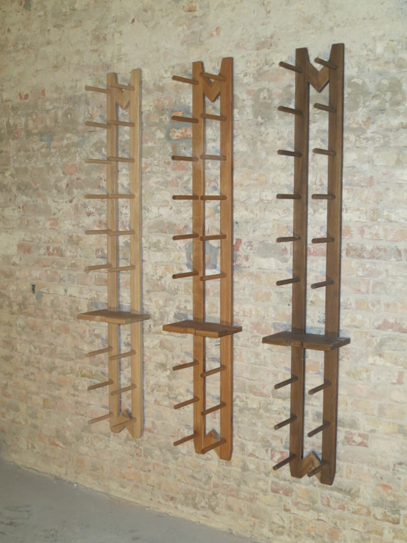 May include: Three wooden wall-mounted shelves with a unique design. Each shelf has a series of evenly spaced dowels for hanging items. The shelves are made of different shades of wood, ranging from light to dark brown.