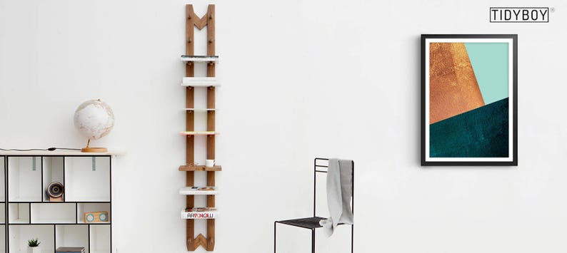 May include: A wooden ladder shelf with five shelves, each with a different color. The shelf is mounted on a white wall. A globe, a small lamp, and a white shelf unit are visible in the background.