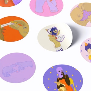 Könnte beinhalten: Eine Sammlung runder Aufkleber mit verschiedenen Illustrationen, darunter Hände, die einen Glückskeks mit dem Text SMASH THE PATRIARCHY halten, ein herzförmiger Spiegel mit demselben Text und eine Person mit einer violetten Sturmhaube.