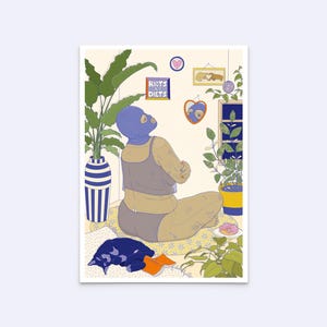 May include: A woman wearing a blue balaclava sits on a floral patterned cushion with her arms crossed. She is looking up at a sign that says "Riots are my diet." There are plants, a mirror, and a framed picture on the wall behind her.