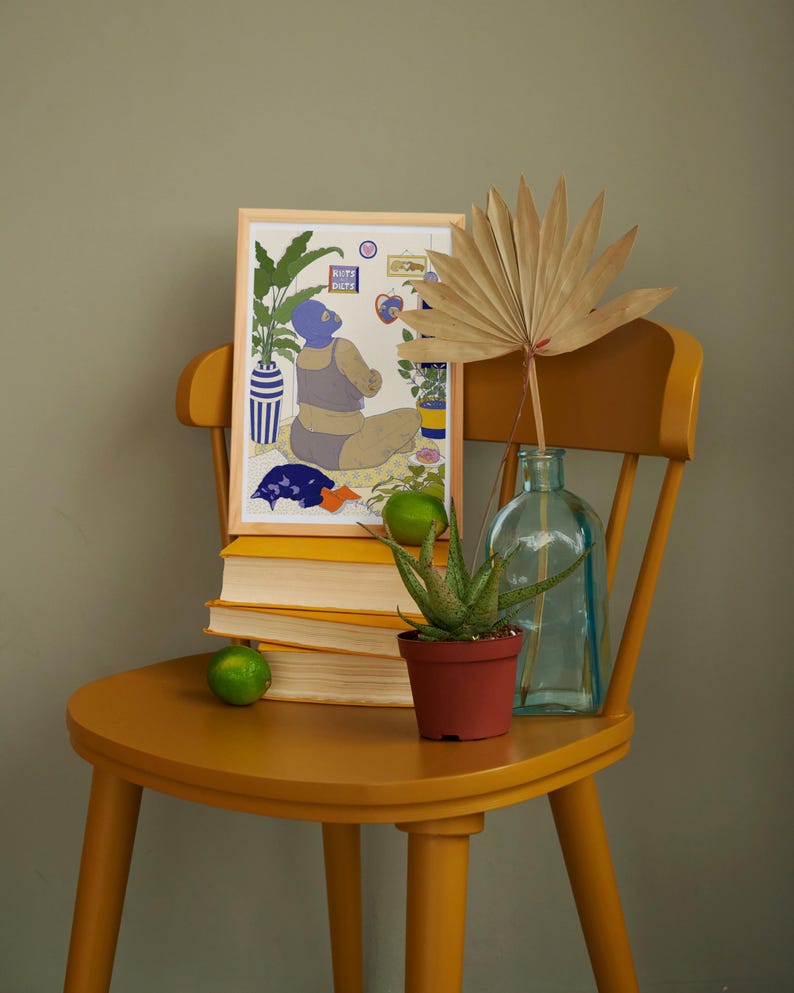 May include: A framed illustration of a person wearing a blue swimsuit and a blue face mask, sitting in a room with plants and a window. The illustration is on a yellow chair with a stack of books, a potted plant, and a glass bottle.