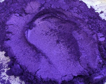 Op de afbeelding: Close-up van een hoop glinsterend paars pigmentpoeder. Het poeder heeft een metallic glans en een fijne textuur. De kleur is een diep violet met blauwe ondertonen, wat een aantrekkelijk visueel effect creëert. Waarschijnlijk gebruikt voor knutselen of cosmetica.