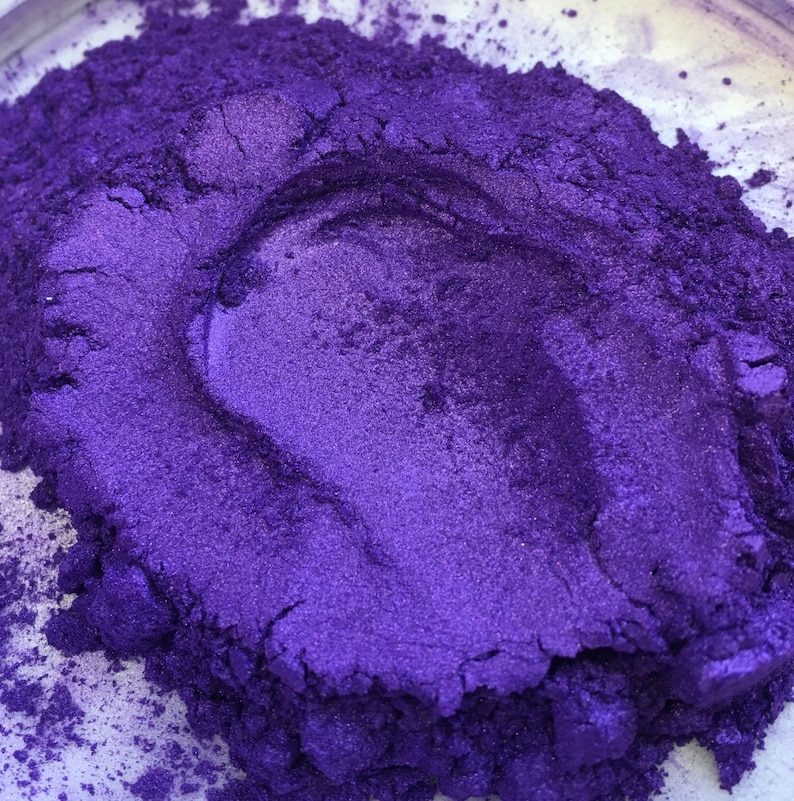 Puede incluir: Primer plano de un mont&oacute;n de polvo de pigmento morado brillante. El polvo tiene un brillo met&aacute;lico y una textura fina. El color es un violeta intenso con matices azules, creando un efecto visual atractivo. Probablemente utilizado para manualidades o cosm&eacute;ticos.