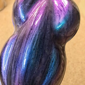 May include: A teardrop-shaped object with a glossy, iridescent finish. The colour shifts from deep blues and purples to vibrant teal and magenta, creating a dynamic effect. The surface has a smooth, flowing appearance.