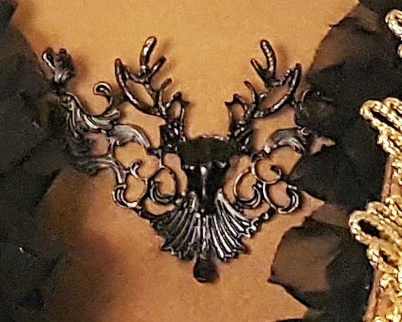 May include: A black metal deer head design with intricate details. The design is ornate and features a stylized deer head with antlers.