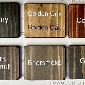 May include: Six wood stain samples in square tiles. The stains are Ebony, Golden Oak, Cognac, Dark Walnut, Briarsmoke, and Gray.