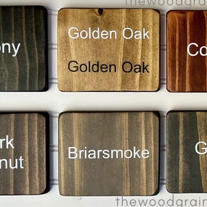 May include: Six wood stain samples in square tiles, labeled with their names: Ebony, Golden Oak, Cognac, Dark Walnut, Briarsmoke, and Gray.