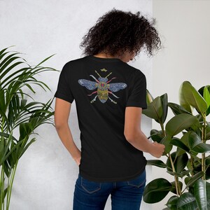 May include: A black t-shirt with a detailed illustration of a bee with a crown on its head. The bee is made up of intricate patterns and designs, including a red heart in its center.