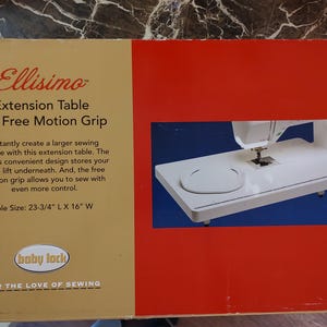 Peut inclure: Boîte pour une table d'extension Ellisimo et une poignée de mouvement libre. La boîte est rouge et beige avec du texte et une image d'une machine à coudre blanche sur une table blanche. La table mesure 60.3 cm L x 40.6 cm l.