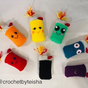 May include: Seven crocheted lighters in various colors, including red, orange, yellow, green, blue, purple, and black. Each lighter has a flame on top and a cute face.