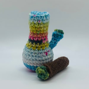 May include: A crocheted blue, green, and pink bong with a brown crocheted joint.