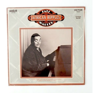 Puede incluir: Una portada de álbum de vinilo vintage con una foto en blanco y negro de Fats Waller tocando el piano. El título del álbum es "African Ripples" y la discográfica es RCA Victor.