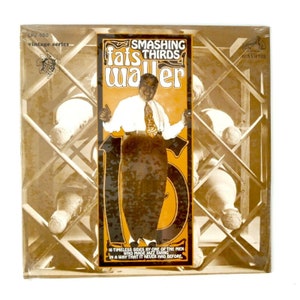 Puede incluir: Una portada de álbum de vinilo vintage con una foto en blanco y negro de Fats Waller, un músico de jazz, con el texto "Smashing Thirds Fats Waller" y "16 Timeless Sides by one of the men who made jazz swing in a way that it never had before."