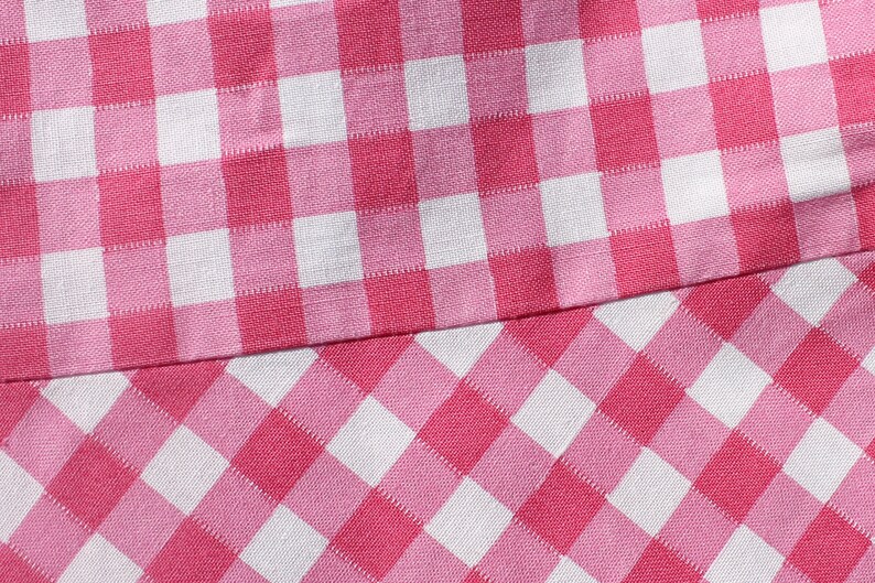 May include: Pink and white checkered fabric with a different pattern on the bottom half. The top half has a larger square pattern, while the bottom half has a smaller diamond pattern.