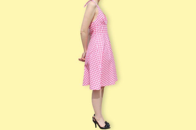 May include: A pink and white gingham dress with a halter neckline and a fitted bodice. The dress has a full skirt and is knee-length.