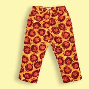 Puede incluir: Pantalones naranjas con un estampado abstracto rojo y blanco.