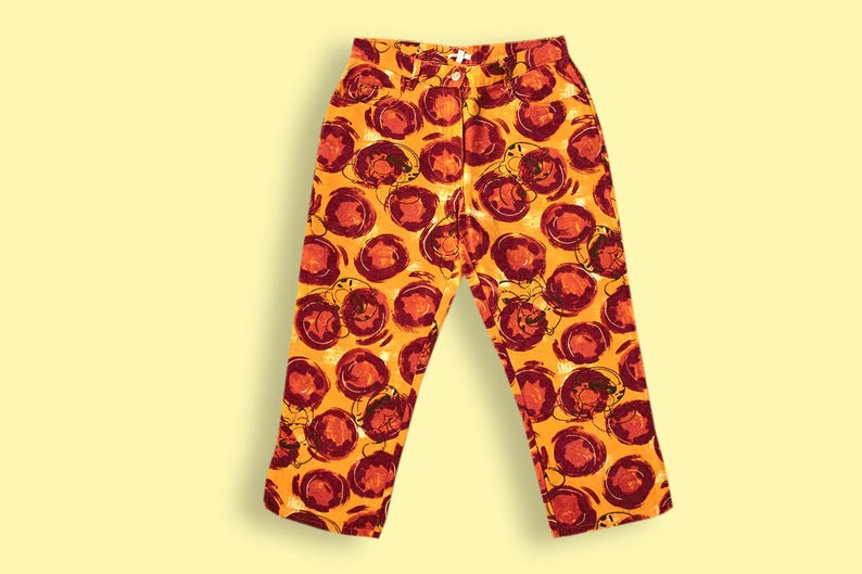 Puede incluir: Pantalones naranjas con un estampado abstracto rojo y blanco.