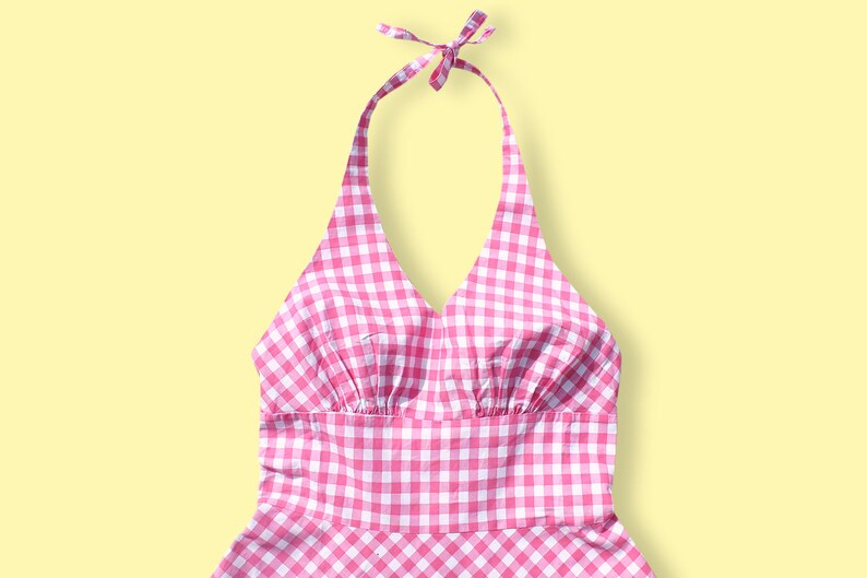 May include: A pink and white gingham halter dress with a V-neckline and a gathered bodice.