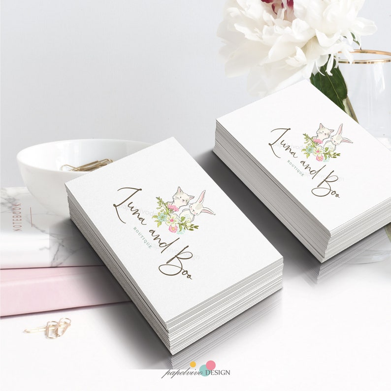 May include: Stack of white business cards with a logo featuring two cartoon bunnies with pink flowers and the text "Luna and Boo Boutique".