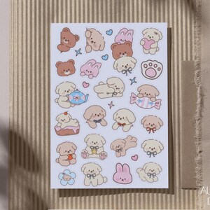 Peut inclure: Une planche d'autocollants rectangulaire pr&eacute;sentant une collection de petites illustrations de style dessin anim&eacute; de chiots, de lapins et d'oursons marron et cr&egrave;me. Les motifs incluent diverses poses, des accessoires comme des n&oelig;uds et une th&eacute;i&egrave;re.