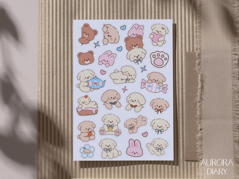 Peut inclure: Une planche d'autocollants rectangulaire pr&eacute;sentant une collection de petites illustrations de style dessin anim&eacute; de chiots, de lapins et d'oursons marron et cr&egrave;me. Les motifs incluent diverses poses, des accessoires comme des n&oelig;uds et une th&eacute;i&egrave;re.