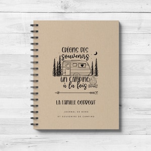 May include: A brown spiral bound notebook with a black and white illustration of a camper van, trees, and a campfire. The text on the cover reads "Créons des souvenirs un camping à la fois La famille Godrout Journal de bord et souvenirs de camping".