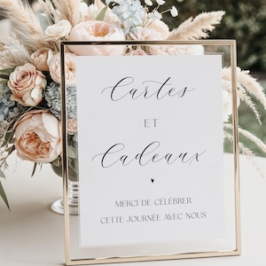 Peut inclure: Un panneau doré avec l'inscription "Cartes et Cadeaux" en écriture élégante. Le panneau comprend également le texte "Merci de célébrer cette journée avec nous". Un arrangement floral de fleurs roses et crème est en arrière-plan.