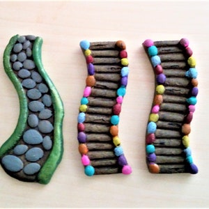 May include: Five miniature garden path pieces. Two are curved paths made of gray stones with green borders. Two are curved paths made of brown logs with colorful dots. One is a straight path made of gray rocks with pink dots.