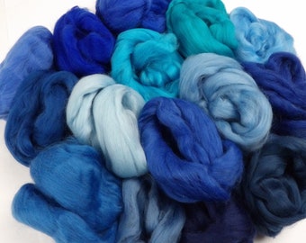 May include: A collection of blue and teal wool roving in various shades. The roving is arranged in a circle, with the darkest shades in the center and the lightest shades on the outside.