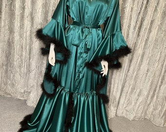 May include: A long, emerald green satin robe with black feather trim. The robe has a shawl collar, a tie belt, and a flowing skirt.