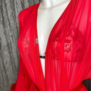 May include: A red sheer robe with a satin sash and feather trim. The robe has a deep V-neckline and is made of a lightweight, flowing fabric.