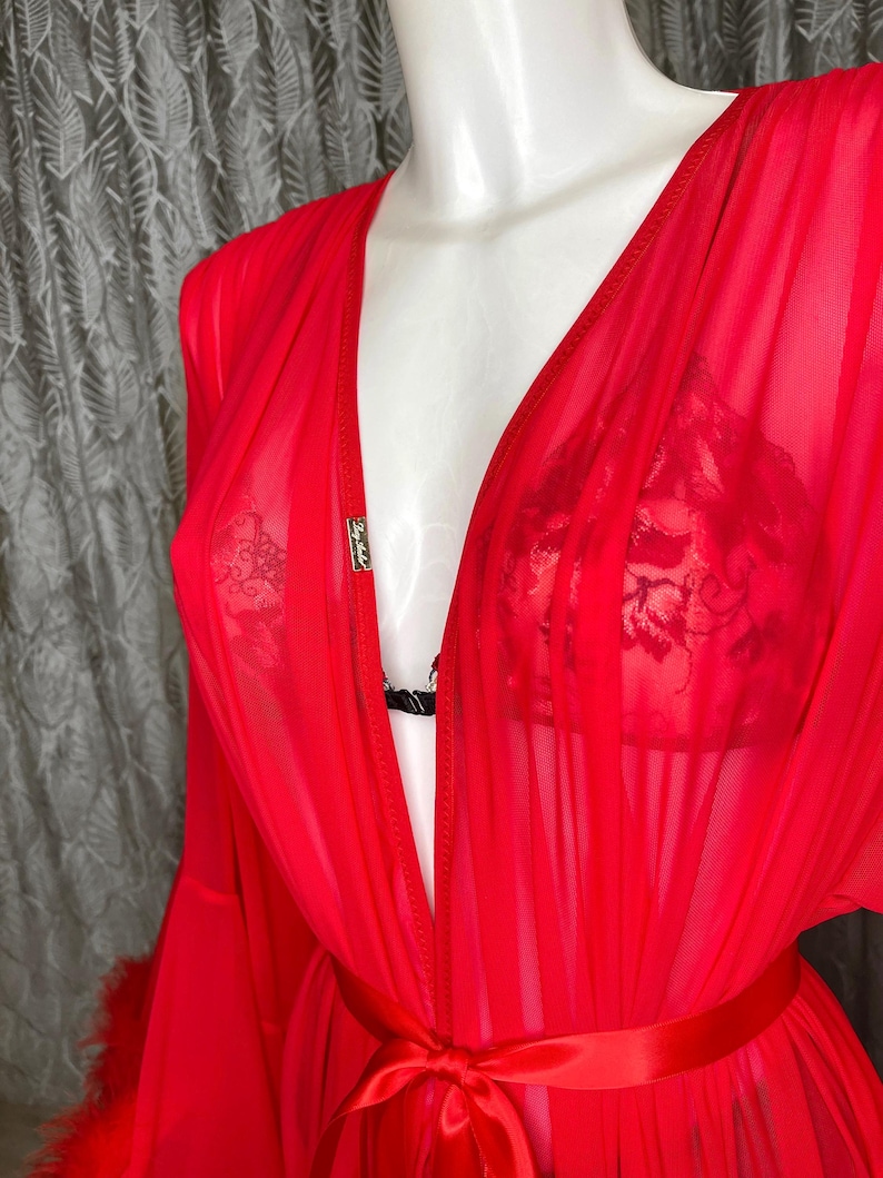 May include: A red sheer robe with a satin sash and feather trim. The robe has a deep V-neckline and is made of a lightweight, flowing fabric.