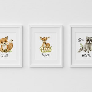 May include: Three framed watercolor illustrations of woodland animals. The first features a fox with the word "SMART" below. The second features a fawn with the word "SWEET" below. The third features a raccoon with the words "and a little bit RASCAL" below.