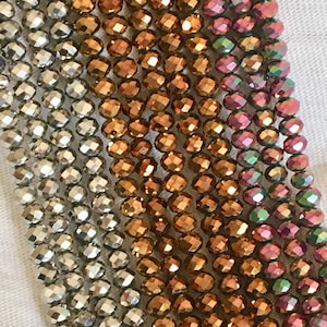 Puede incluir: Primer plano de un accesorio de cuentas con un degradado de colores. Las cuentas transicionan de plata a bronce, luego a un rosa-púrpura con reflejos iridiscentes. Las cuentas están facetadas, captando la luz.