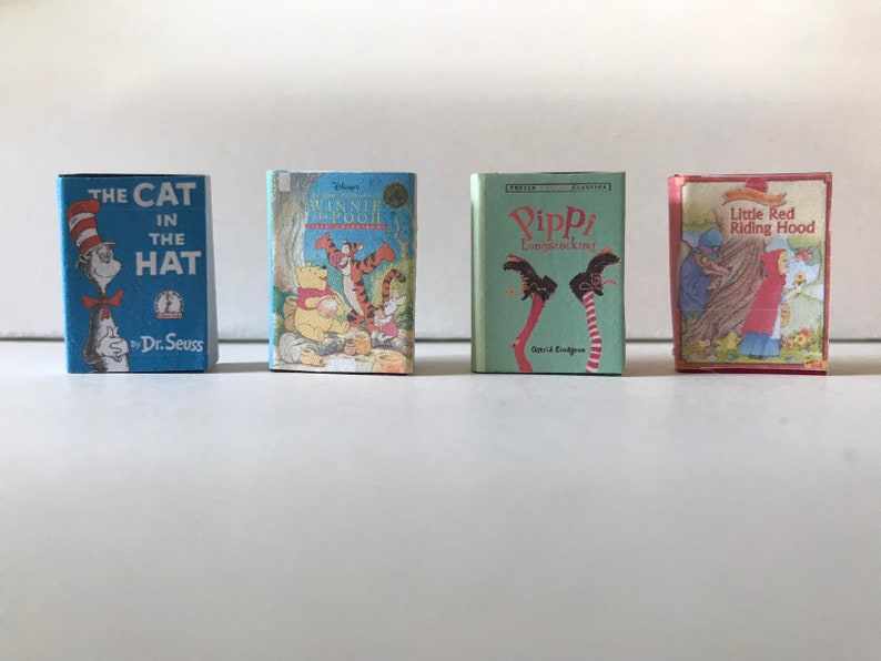 May include: Four miniature hardcover books with colorful covers. The books are titled "The Cat in the Hat" by Dr. Seuss, "Winnie the Pooh", "Pippi Longstocking", and "Little Red Riding Hood".